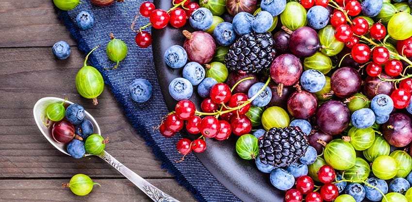 Un piatto di frutta di settembre: mirtilli, ribes, uva e more