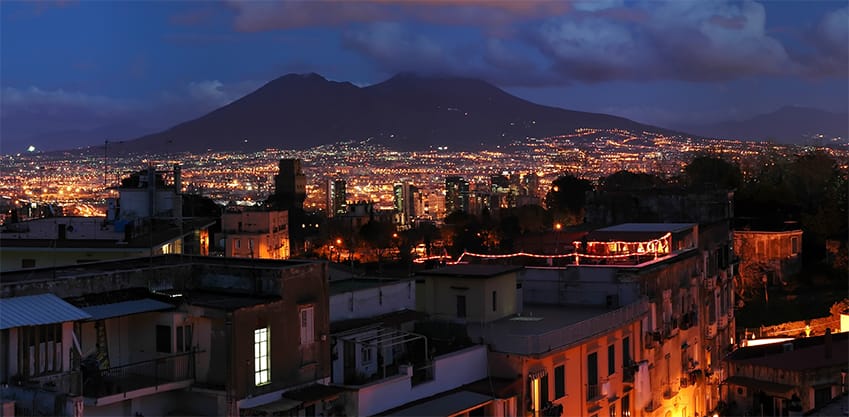 vista di notte di Napoli illuminata con il Vesuvio dietro