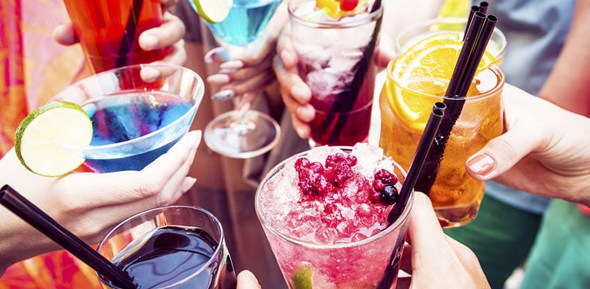 Bicchieri di cocktail estivi e colorati decorati con bacchette e frutta