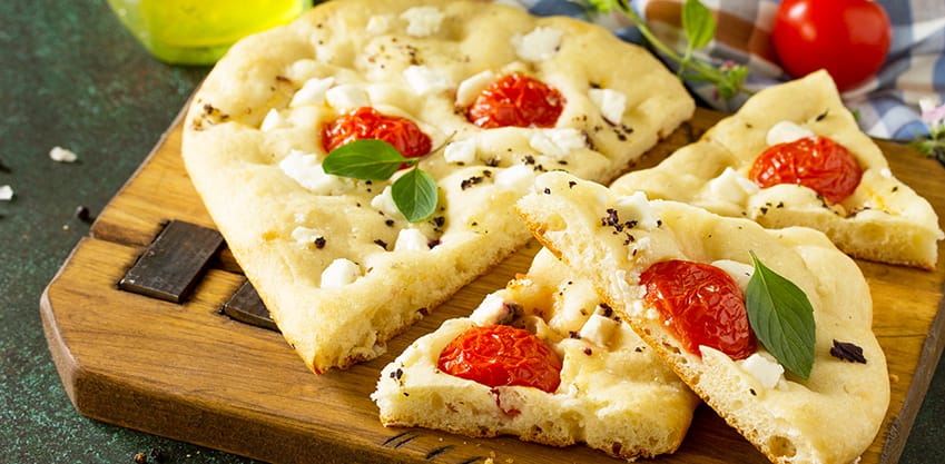 Focaccia con pomodori e basilico su tagliere Focaccia con pomodori e basilico su tagliere