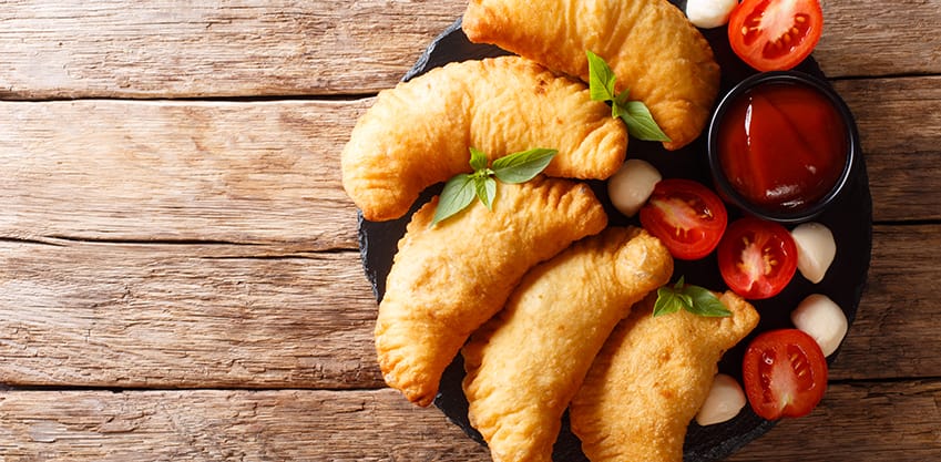 Prova tutte le varianti più golose di un aperitivo a base di panzerotti Piatto con panzerotti, pomodori, salsa e mozzarelline