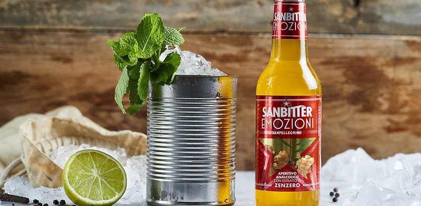 Bottiglia di Sanbitter con estratto di zenzero e barattolo con ghiaccio, menta, limone e spezie