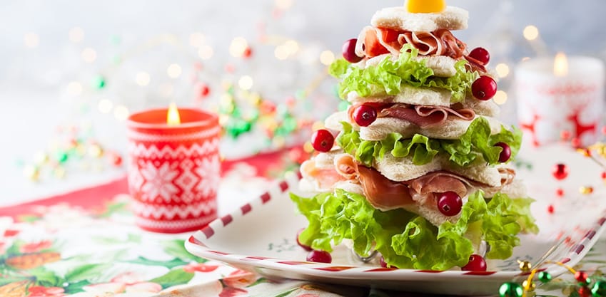 Tartine a forma di albero di natale con tramezzini, insalata e prosciutto